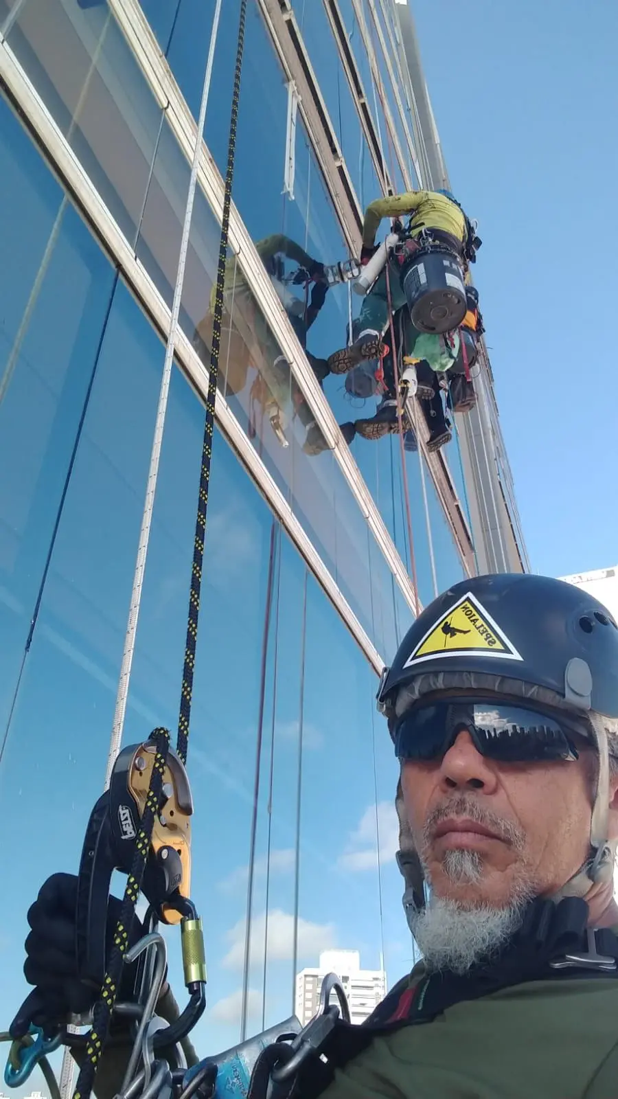 Técnico em acesso por corda trabalhando numa fachada de vidro